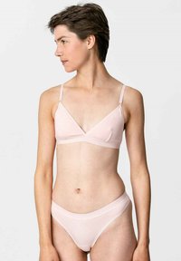 Hellrosa Bralette und passende Unterhose aus glattem Stoff. Der Bralette hat dreieckige Cups und dünne verstellbare Träger.