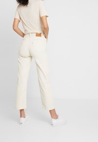 Ljust beige manchesterbyxor med avslappnad passform, kort längd och två bakfickor. Bärs med en beige t-shirt och vita sneakers.