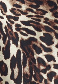 Tkanina s uzorkom leopardove boje ima teksturiranu slonovaču kao pozadinu s hrabrim crnim i smeškim mrljama različitih oblika i veličina.