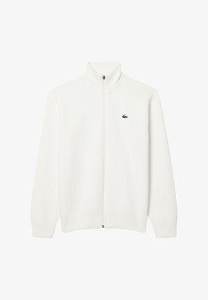 Maglione bianco a coste con zip e colletto alto, dotato di un piccolo logo verde sull'area del petto sinistro. Tessuto morbido, maniche lunghe e vestibilità dritta.