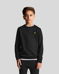 Svart crewneck-tröja i mjukt tyg, med en liten gul logotyp på bröstet och ribbade muddar och nederkant. Stylad med svarta byxor.