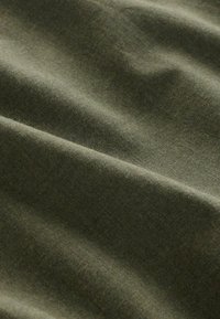 Material de culoare verde măsliniu, cu o textură moale, având ondulații și plieri delicate, evidențiind natura sa ușoară și flexibilă.