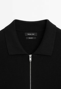 Schwarzer Baumwollpullover mit Reißverschluss und geripptem Strukturmuster. Verfügt über einen flachgestrickten Kragen und einen metallischen Reißverschluss vorne, der ein minimalistisches Design zeigt.