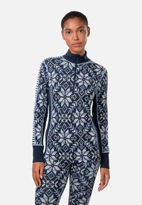 Marineblaues und hellblaues gemustertes Thermo-Oberteil mit Reißverschlusskragen, langen Ärmeln und figurbetontem Schnitt, kombiniert mit passenden gemusterten Leggings.