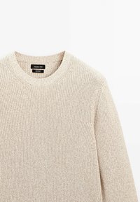 Pull en coton beige tricoté avec col rond et manches longues, avec une étiquette Massimo Dutti au col.