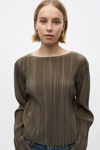 Olijfgroen geplooid long-sleeve shirt met een brede halslijn, zachte textuur en vloeiende uitstraling, gecombineerd met denim jeans.