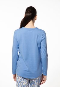 Lichtblauw shirt met lange mouwen en ronde hals, met een gladde textuur en een iets gebogen zoom, gecombineerd met gestreepte lichte broeken.