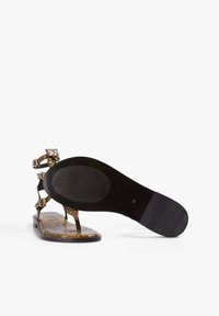 Sandal tipo plano de serpiente marrón con suela negra, que cuenta con dos correas ajustables con hebillas doradas y un diseño de separador para el dedo. 