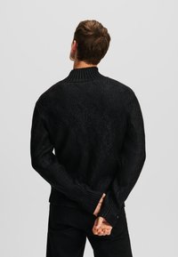 Sort strikket sweater med et tekstureret diamantmønster, ribbet krave og manchetter, i en afslappet pasform og tyk stof.