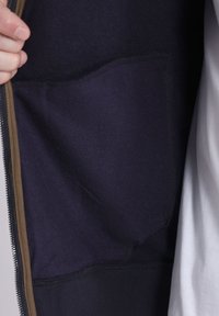 Veste à capuche zippée bleu marine avec une texture douce, dotée d'une poche kangourou et de détails de fermeture éclair brun contrastants.