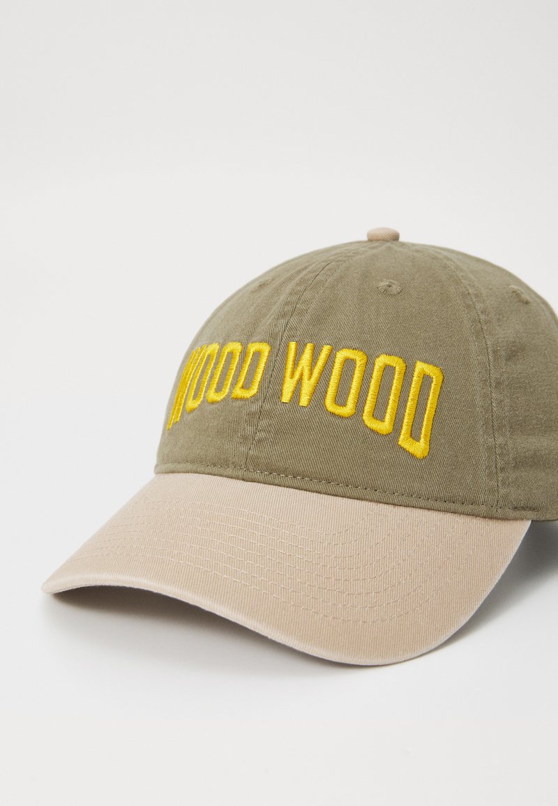 Gorra de béisbol verde oliva con bordado amarillo "WOOD WOOD". Presenta una visera de color marrón claro y textura, y una construcción de tela. Parte trasera ajustable.