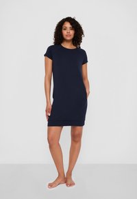 Granatowa sukienka z dzianiny, z krótkimi rękawami, okrągłym dekoltem, bocznymi kieszeniami i luźnym krojem, sięgająca tuż nad kolana.