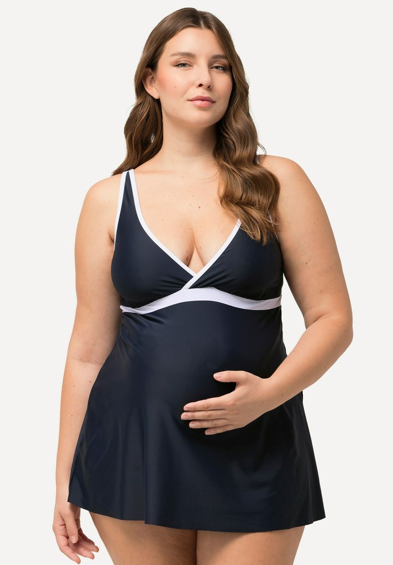 Těhotenské plavky ve navy s bílými akcenty. Obsahuje výstřih do V, nastavitelné ramínka a rozšířenou sukni pro pohodlí a oporu.