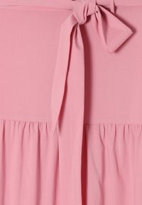 Roze stof met een geplooid detail en een gestrikt strikje in het midden bovenaan, die de textuur en zachte plooien benadrukt.