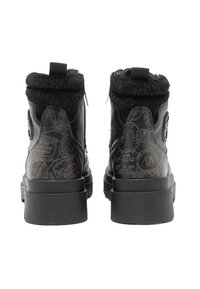 Stivaletti alla caviglia in pelle nera con bordo in pelliccia ecologica, suola piatta e chiusura con cerniera. Sul retro un motivo decorativo che ricorda documenti di viaggio timbrati.