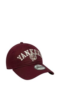 Maroon baseball cap with white "YANKEES" text and logo on front. Cotton material, structured design, curved brim, and adjustable strap.