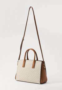 Borsa tote con una parte frontale in tela crema a motivo, dettagli in pelle marrone, doppi manici e una tracolla regolabile. Presenta dettagli in metallo dorato.