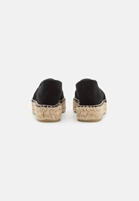 Espadrillas nere in suede con suole in corda di juta, caratterizzate da un design piatto e senza chiusure visibili. Stile minimalista con una morbida texture.