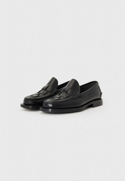 Mocassins en cuir noir avec un design à l'avant tressé, talon plat et bout arrondi. Caractéristiques de détails cousus le long des bords.