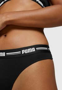 Schwarze Baumwollbikini-Unterwäsche im Stil mit breitem elastischen Bund, versehen mit dem weißen "PUMA"-Logo und gestreiften Akzenten. Glatte Textur, figurbetontes Design.