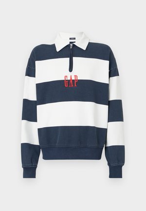Sweatshirt listrado em azul-marinho e branco com gola zippada, apresentando o logótipo bordado "GAP" em vermelho ao centro. Tecido suave, ajuste relaxado.