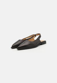 Chaussures slingback en cuir noir avec un design à bout pointu, semelle plate et finition épurée, arborant un style minimaliste sans matériel visible.