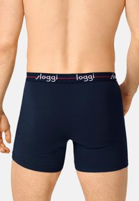 Marineblaue Boxershorts aus Jersey-Stoff, mit glatter Textur und einem mit Logo versehenen Bund in roten Akzenten.