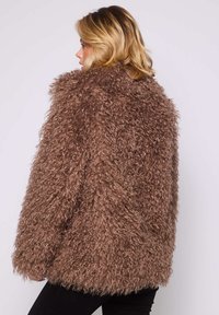 Cappotto in pelliccia ecologica marrone con un design textures e soffice, dalla vestibilità ampia e maniche lunghe. Senza chiusure visibili o fantasie.