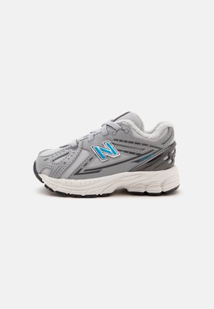 Scarpa sportiva New Balance grigia e bianca con logo blu, suola ammortizzata e rivestimento interno morbido, mostrata di profilo su sfondo bianco.