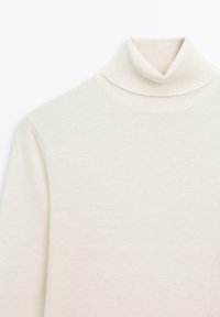 Roomkleurige coltrui gemaakt van zachte gebreide stof. Heeft een aansluitende pasvorm met geribde hals en manchetten.