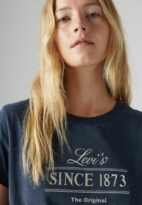 Camiseta de algodón azul marino con un logo impreso en blanco que dice "Levi's SINCE 1873 The Original" en el pecho y un cuello redondo clásico.