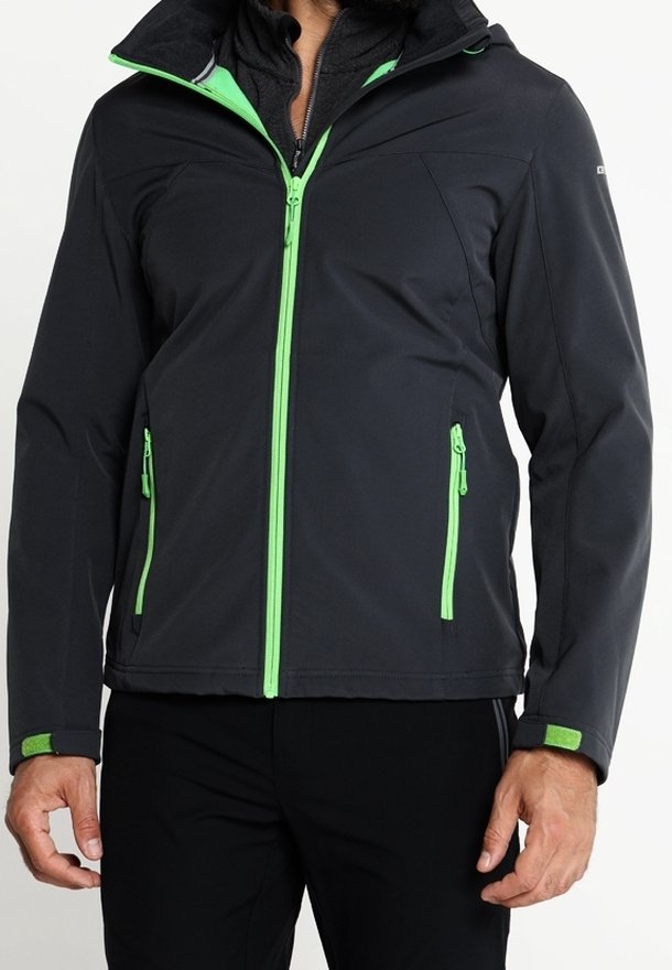 Homme portant une veste sombre avec une fermeture éclair vert vif et des accents aux poches, fermeture éclair avant fermée, manches avec poignets verts réglables.