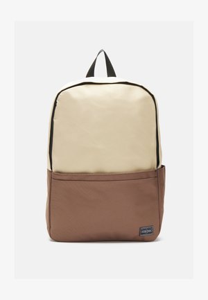 Beige ja pruun seljakott, mis on valmistatud vastupidavast kangast, sisaldab suurt peamist osa, esikäiku, musta luku ja ülemist kanda.