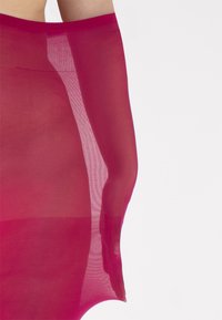 Collant fucsia trasparente con una texture liscia e una fascia alta in vita, caratterizzati da un design senza cuciture che si estende fino alla parte superiore della coscia.