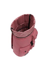 Un sac à dos rose à rabat fabriqué en tissu résistant, avec une doublure intérieure lisse, présentant une poche à snap et du matériel de fermeture ajustable.