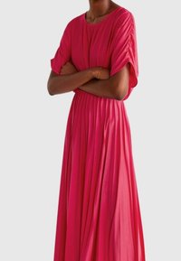 Robe rose longue et fluide avec des manches courtes et larges, et une taille froncée. Fabriquée en tissu léger avec une texture lisse et un design plissé.