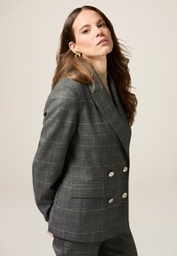 Blazer grigio a quadri doppiopetto con bottoni argentati, realizzato in tessuto testurizzato, con ampi revers e vestibilità su misura.