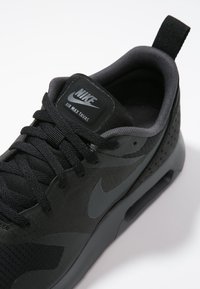 Svart Nike Air Max Tavas-sneaker med snördesign, vadderad krage och synlig luftkudde på vit bakgrund.