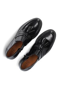 Zwarte lederen instappers met een gladde afwerking, voorzien van een decoratieve kwast en gestikte details langs de zool. Bruine binnenvoering zichtbaar.