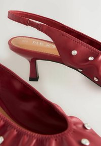 Punaiset nahkaiset slingback-kengät, joissa on matala korko, rypistyksellinen muotoilu, koristeelliset kirkkaat strassit ja pehmustettu pohja.