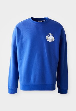 Blue sweatshirt made of cotton with a crew neck and long sleeves. Features a white logo patch on the chest and ribbed cuffs and hem.