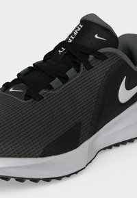 Sort og grå Nike Air Infinity løbesko med hvid swoosh-logo og sorte snørebånd, der viser side- og frontdetaljer.