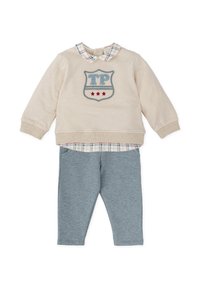 Sudadera beige con logotipo de escudo azul y rojo, cuello de cuadros, combinada con leggins gris claro. Mezcla de algodón suave, diseño informal.