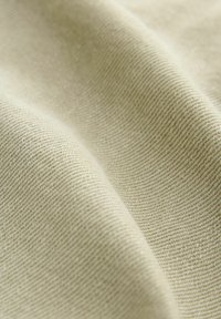 Light beige fabric with a textured, woven pattern, displaying a smooth, soft surface and slight sheen in natural light.