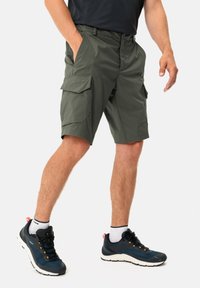 Grüne Cargo-Shorts aus leichtem Stoff, mit mehreren Taschen und bequemer Passform, kombiniert mit marineblauen Wanderschuhen und weißen Socken.