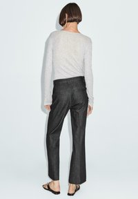 Gray long-sleeve top paired with dark gray tailored trousers, featuring a straight leg cut and back pockets, on a light background.
