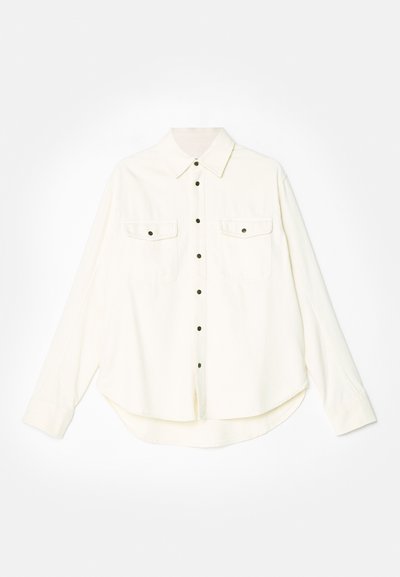 Camisa blanca de botones con mangas largas, dos bolsillos en el pecho, botones negros y un dobladillo curvado. Fabricada con una tela suave y texturizada.