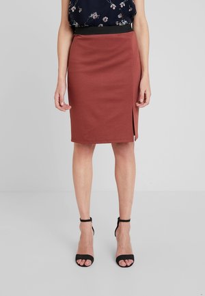 Brązowa ołówkowa spódnica z bocznym rozcięciem. Gładka tkanina, dopasowany krój oraz kontrastujący czarny pas w talii. Całość uzupełniają czarne sandały na ramiączkach.