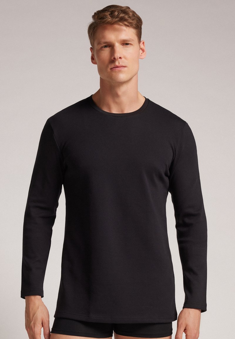 Zwarte shirt met lange mouwen, gemaakt van katoen, met een ronde halslijn en platte naden, met een ontspannen pasvorm en een gladde textuur.