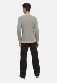 Hellegrau gestrickter Pullover mit strukturiertem Muster, Rundhalsausschnitt, gerippten Bündchen und Saum, kombiniert mit schwarzen, lockeren Hosen.